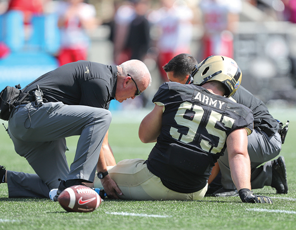 A member of the Athletic Training staff tends to an on-field injury.